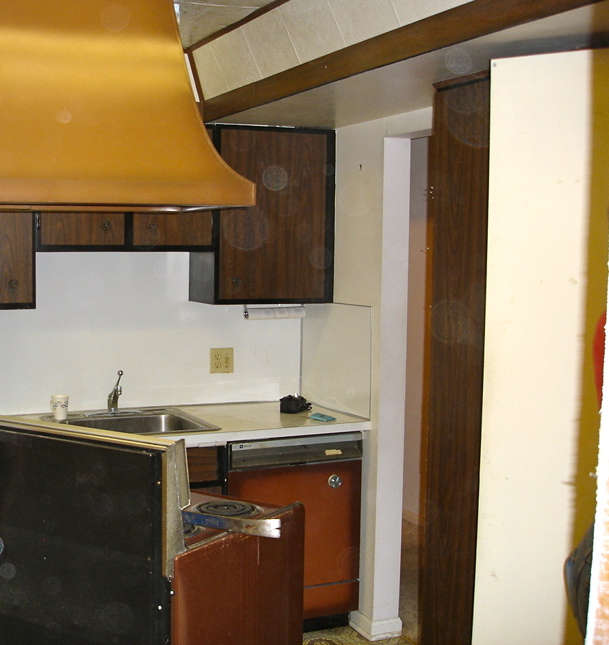 The second kitchen before renovation, with dated cabinets and a copper range hood